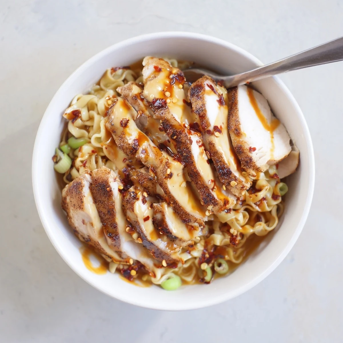 Fiery Chicken Ramen with Creamy Garlic Sauce topped with green onions and chili oil.  