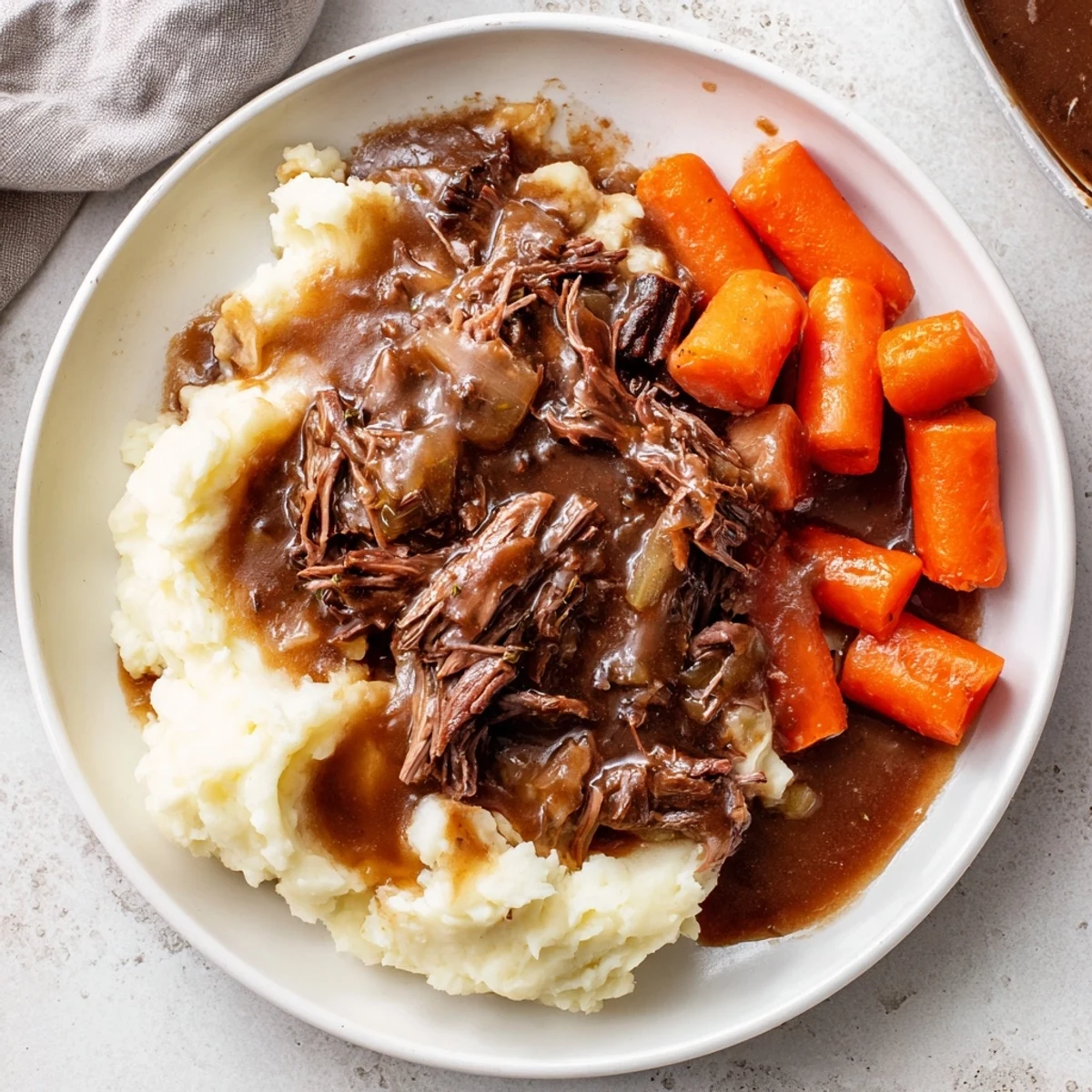 Fork-tender Slow Cooker Pot Roast with vegetables and a generous serving of creamy mashed potatoes.