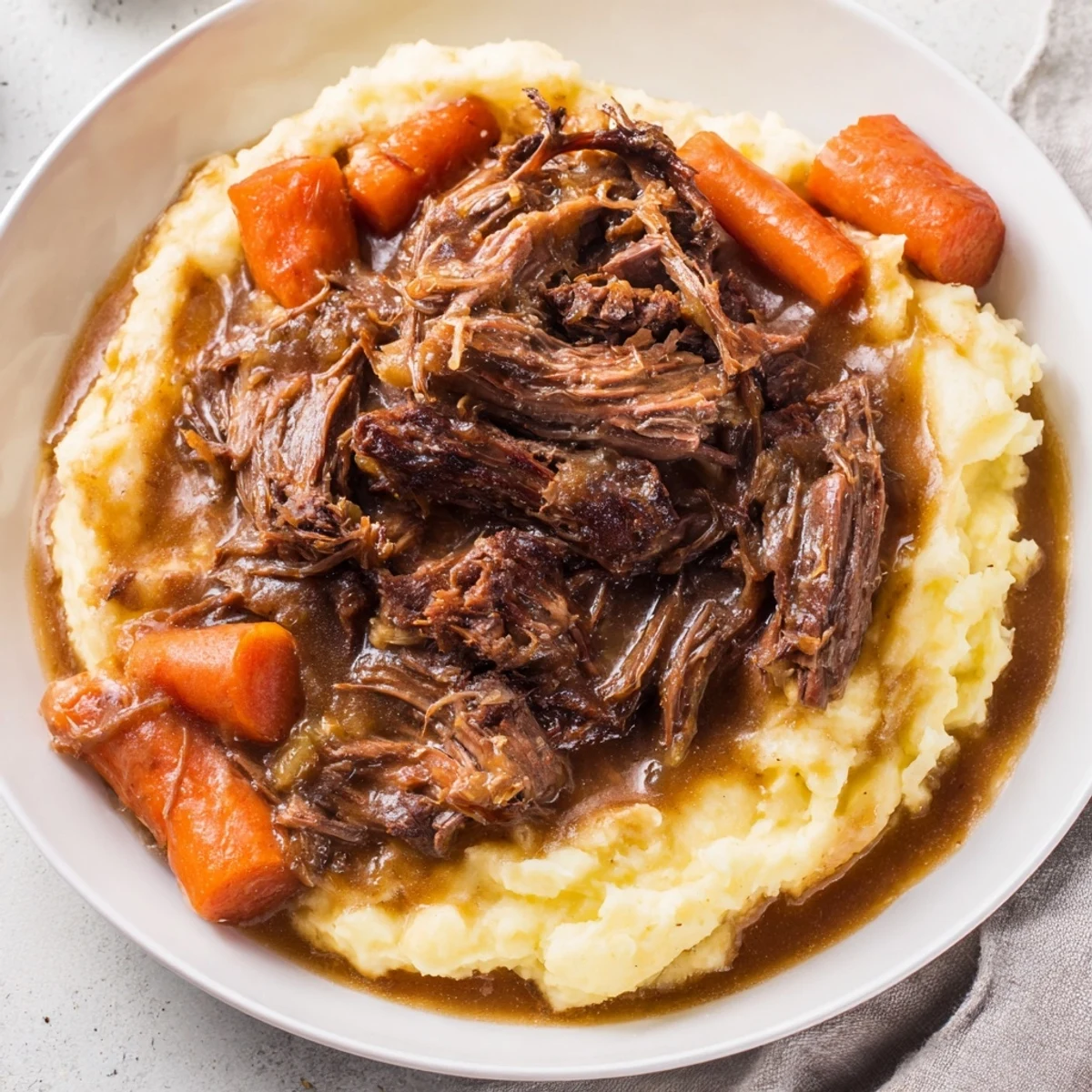 Tender Slow Cooker Pot Roast resting on fluffy mashed potatoes, ready to be served.