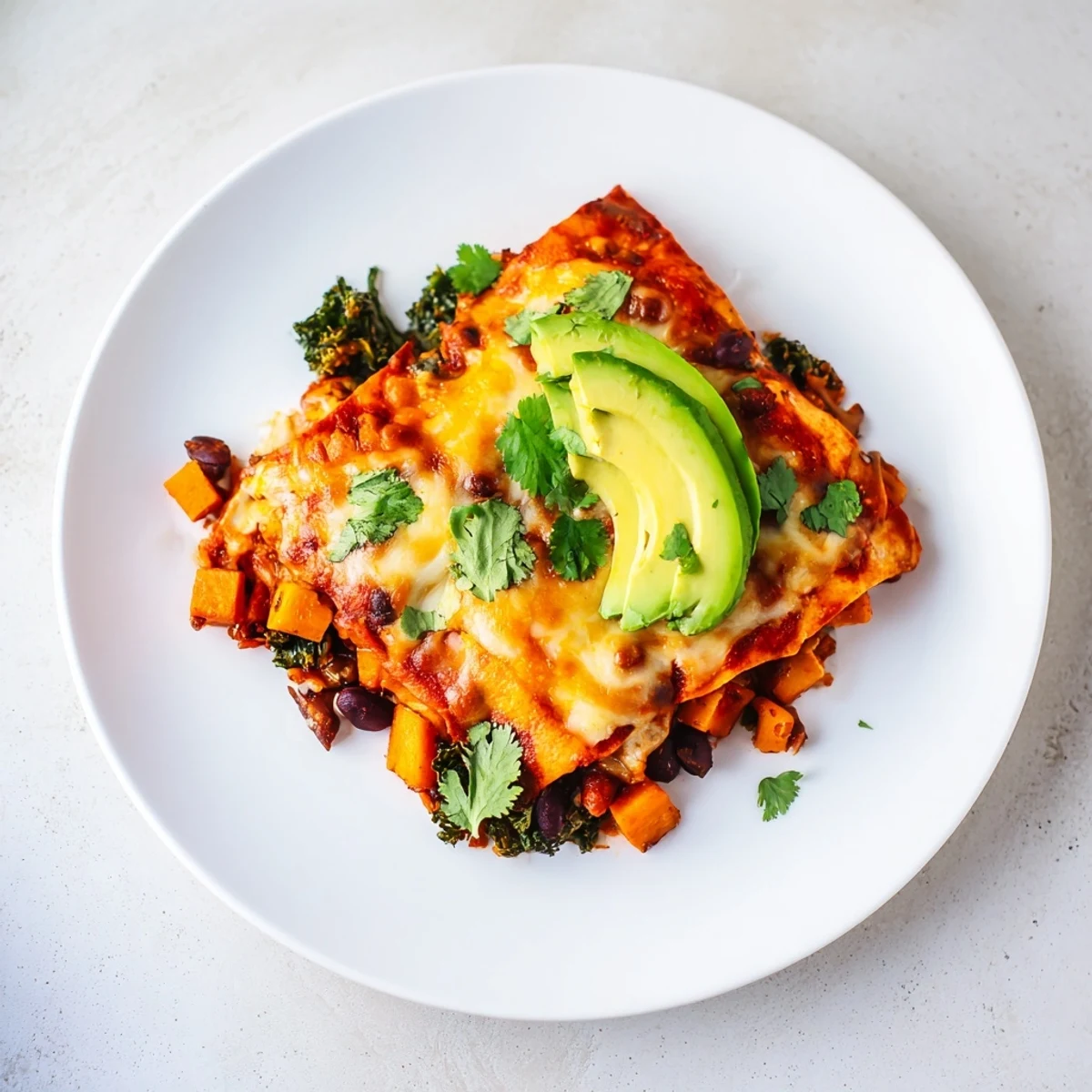 Golden, bubbly One-Pan Sweet Potato, Black Bean & Kale Enchiladas, perfect for a flavorful weeknight vegetarian meal.