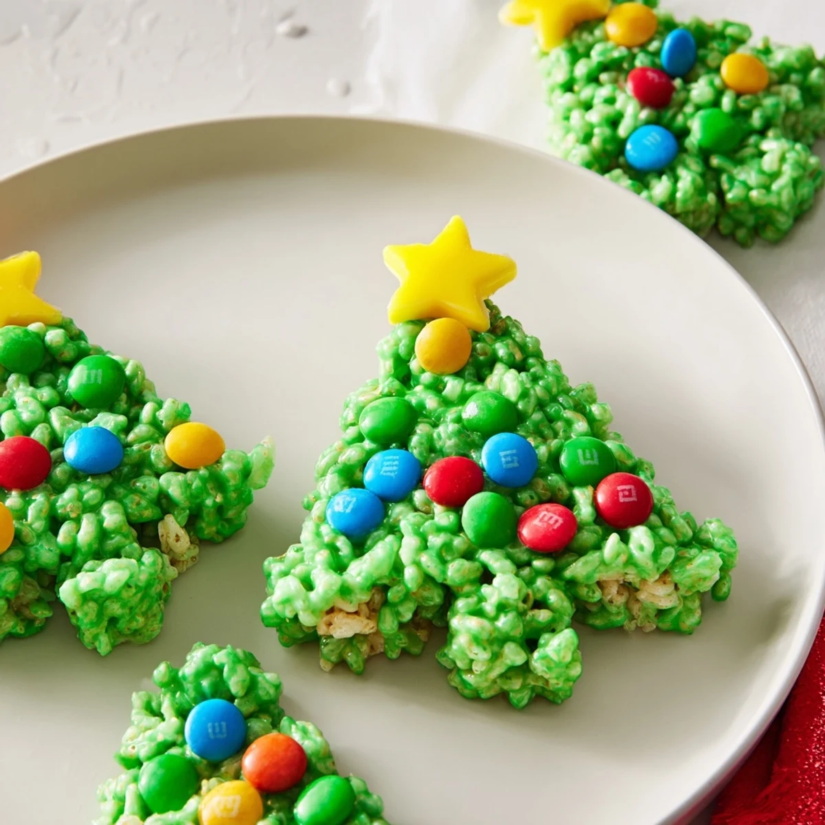 Homemade Christmas Tree Rice Crispy Treats shaped like trees, ready to eat, with pretzel trunks and star candies.