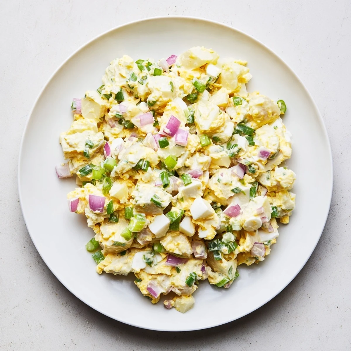 A vibrant bowl of Chopped Egg and Potato Salad, garnished with fresh herbs and ready to serve.