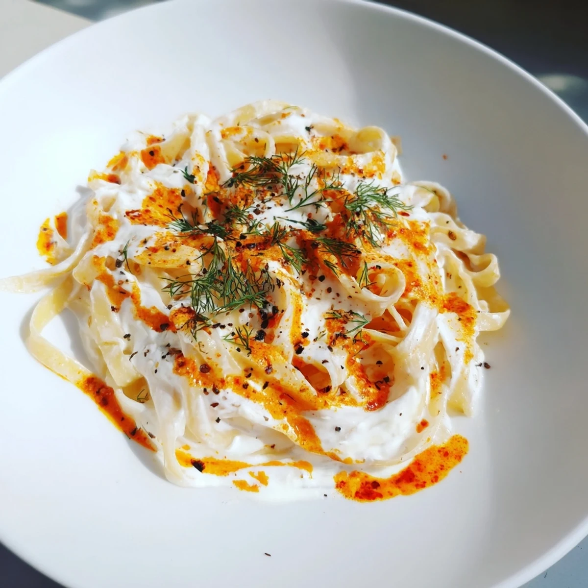 A steaming bowl of Turkish pasta with paprika butter, garnished with fresh herbs, ready to be enjoyed.