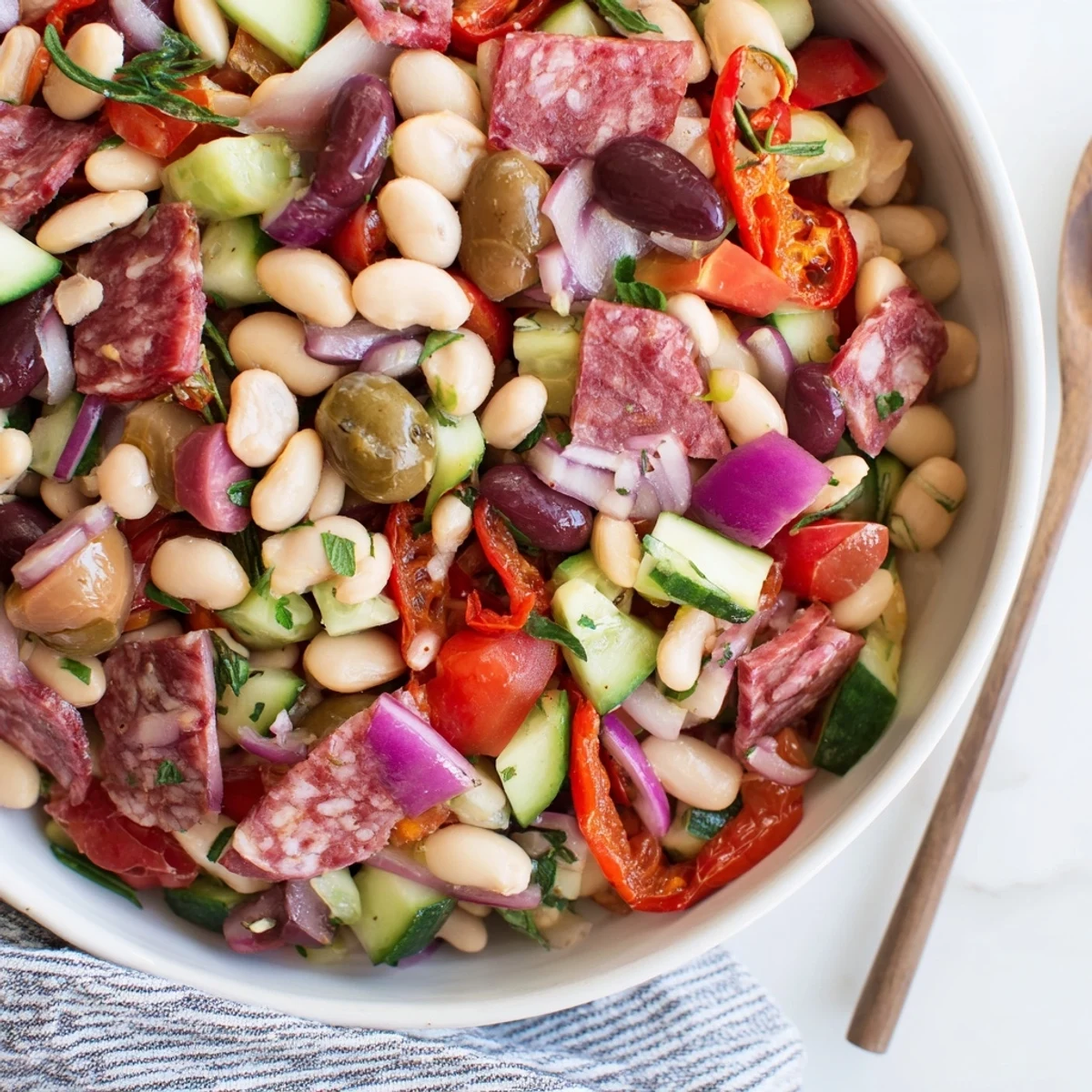 A generous serving of Mediterranean Dense Bean Salad with salami, showcasing colorful fresh ingredients.