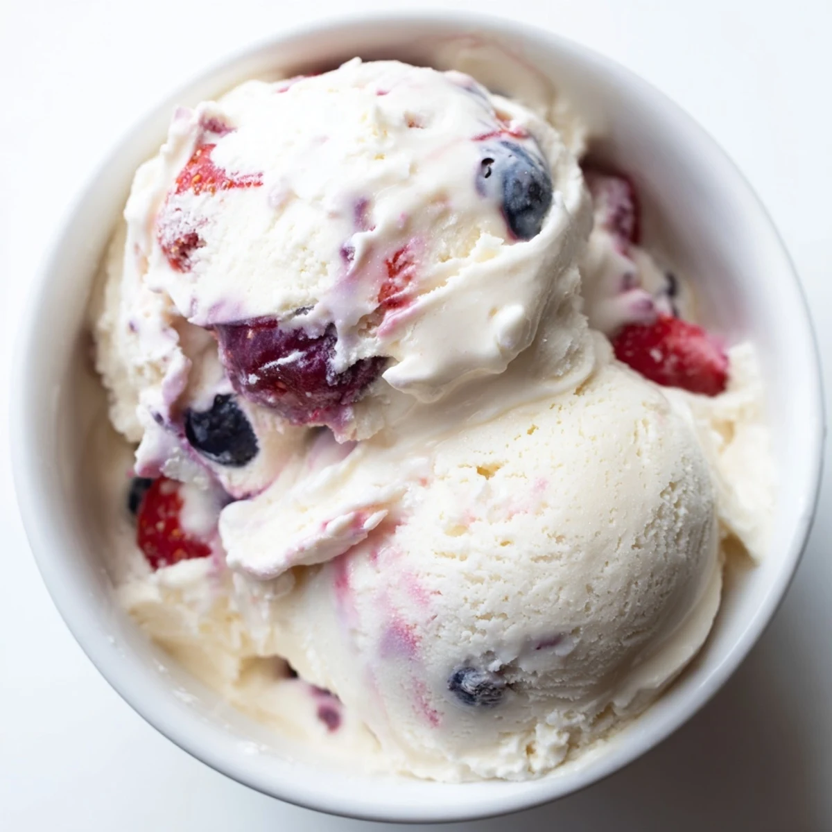 Enjoy a scoop of this healthy cottage cheese ice cream, with vibrant red and blue berry pieces.
