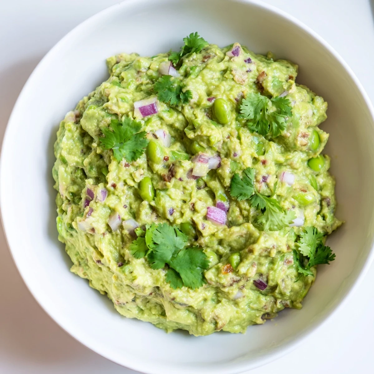Bright green Edamame Guacamole, a flavorful dip, ready to enjoy alongside your favorite snacks and appetizers.