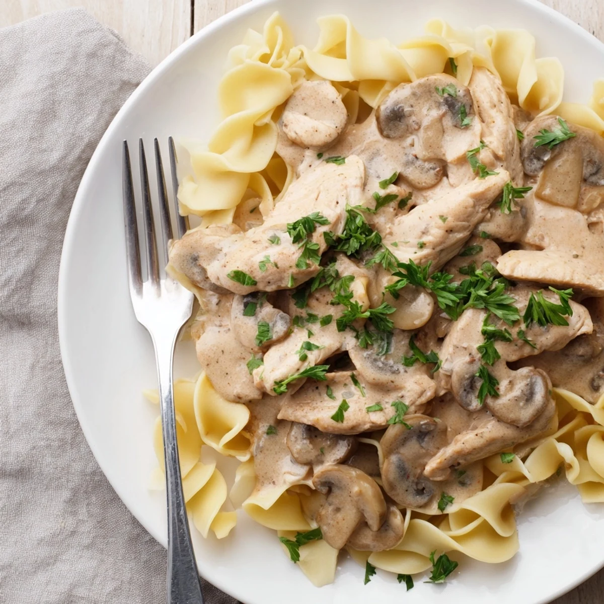 Savory chicken and mushroom stroganoff served atop a bed of egg noodles, with a side salad for a balanced weeknight meal.
