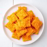 Close-up of baked Crispy Cheeto Cheese Crackers, showcasing the texture, with hints of red paprika, ready to eat.