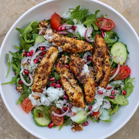 Sliced Holiday Black Pepper Chicken & Yogurt Salad atop vibrant greens and red bell peppers, a festive meal.