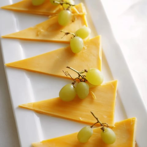 A vibrant photo of a festive The Tannenbaum Border cheese board with green grapes and cheese trees.
