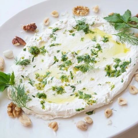 Creamy soft cheese "Fossil Record" appetizer with pressed herbs and rustic nuts looks delicious.