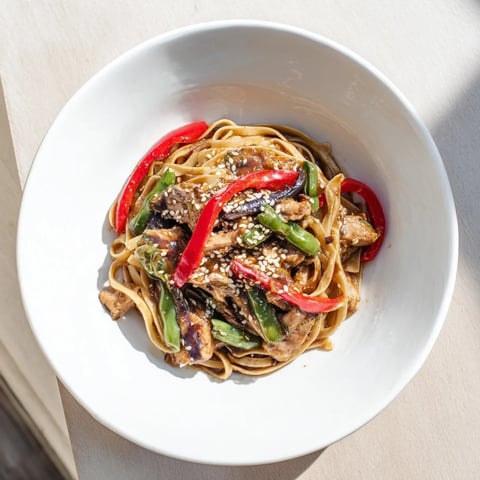 Steaming bowl of Sesame Hoisin Ground Chicken Pasta, a flavorful dish with colorful bell peppers.