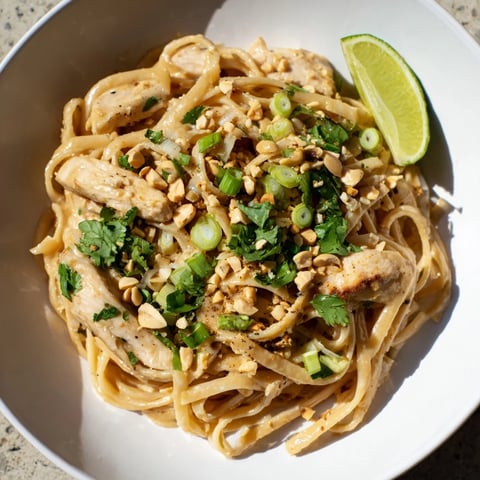 Steaming Thai Peanut Chicken Pasta, a delicious main dish, garnished with fresh herbs and peanuts.