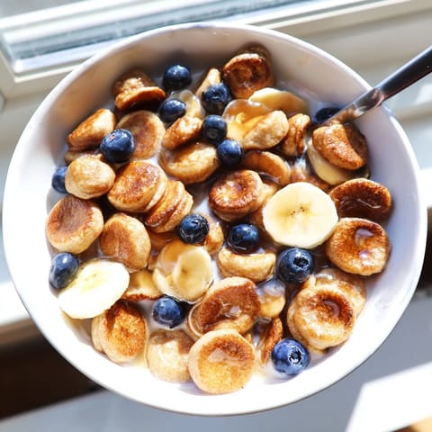 Fluffy bite-sized pancakes for breakfast, served with milk and sliced bananas.  