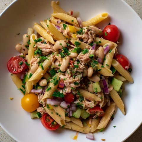 A bowl of Spicy Tuna and White Bean Pasta Salad, tossed with fresh veggies and zesty dressing.