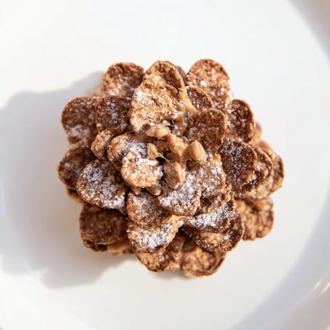 These festive pinecone-shaped nut butter snacks coated with crunchy cereal, perfect for winter snacking.