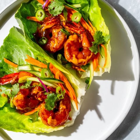 Close-up of delicious shrimp lettuce cups, showing juicy shrimp and crunchy veggies with a tangy sauce.