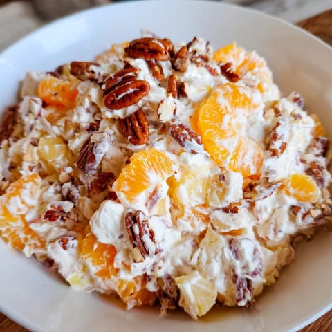 Close-up of the refreshing, chilled Elevated Ambrosia Salad, topped with toasted pecan pieces and coconut.