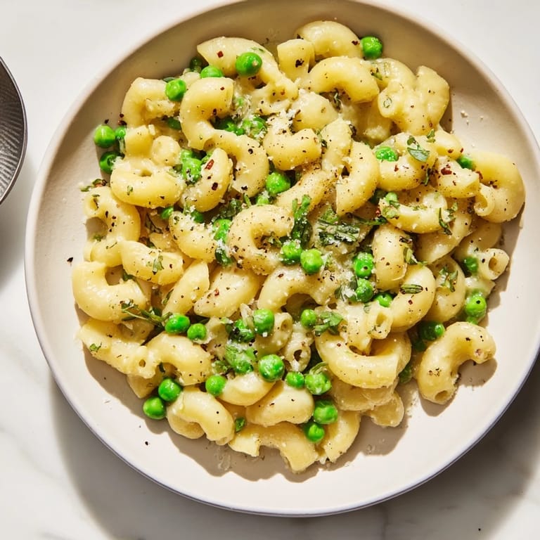 A close-up of steaming macaroni and peas; the delightful aroma of garlic and cheese.