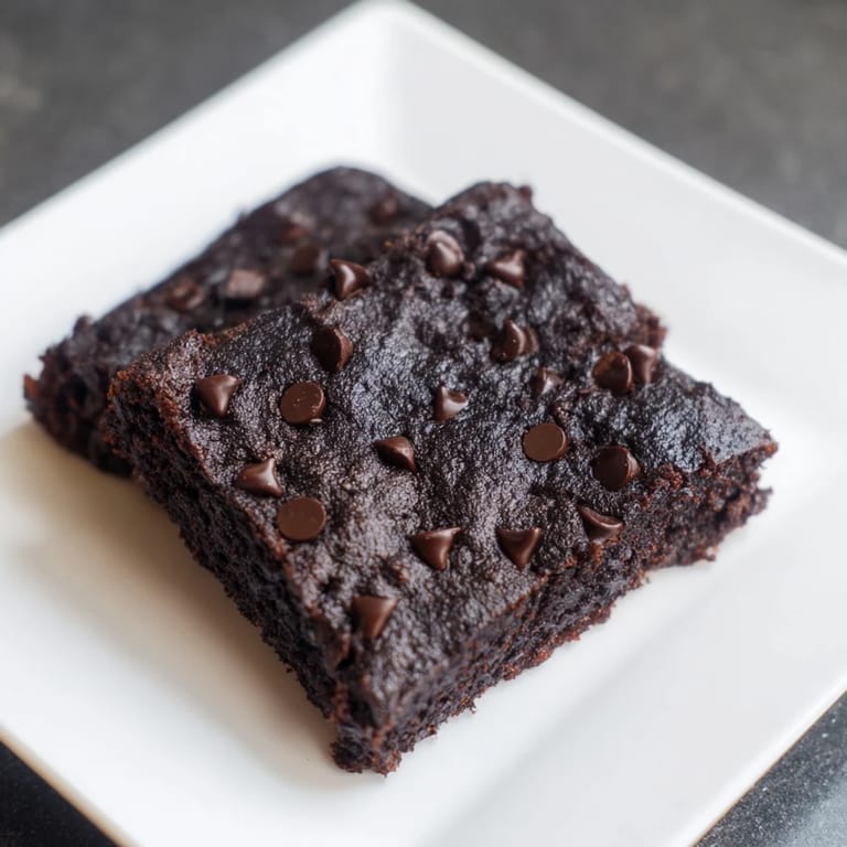 A square of rich Black Bean Brownies, perfectly baked, ready to serve with a scoop of vanilla ice cream.