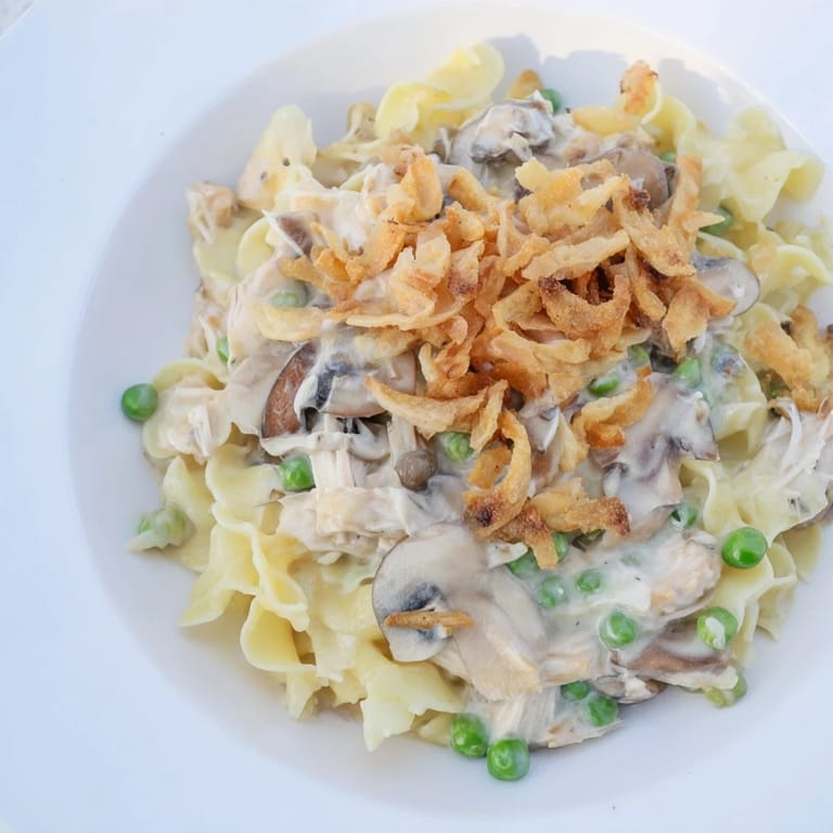 A close-up view of creamy tuna noodle casserole topped with crunchy fried onions, ready to eat.