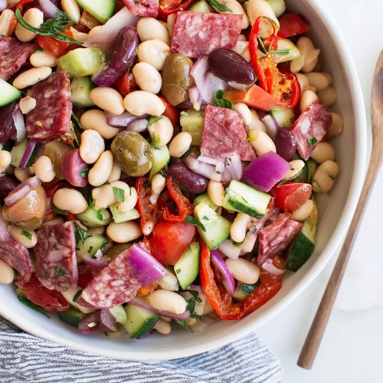 A generous serving of Mediterranean Dense Bean Salad with salami, showcasing colorful fresh ingredients.