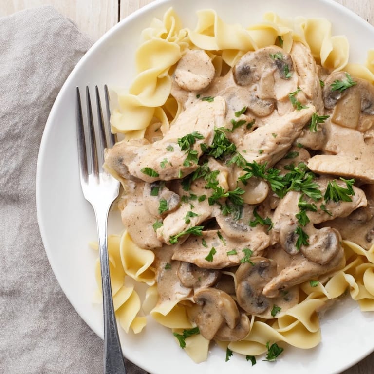 Savory chicken and mushroom stroganoff served atop a bed of egg noodles, with a side salad for a balanced weeknight meal.