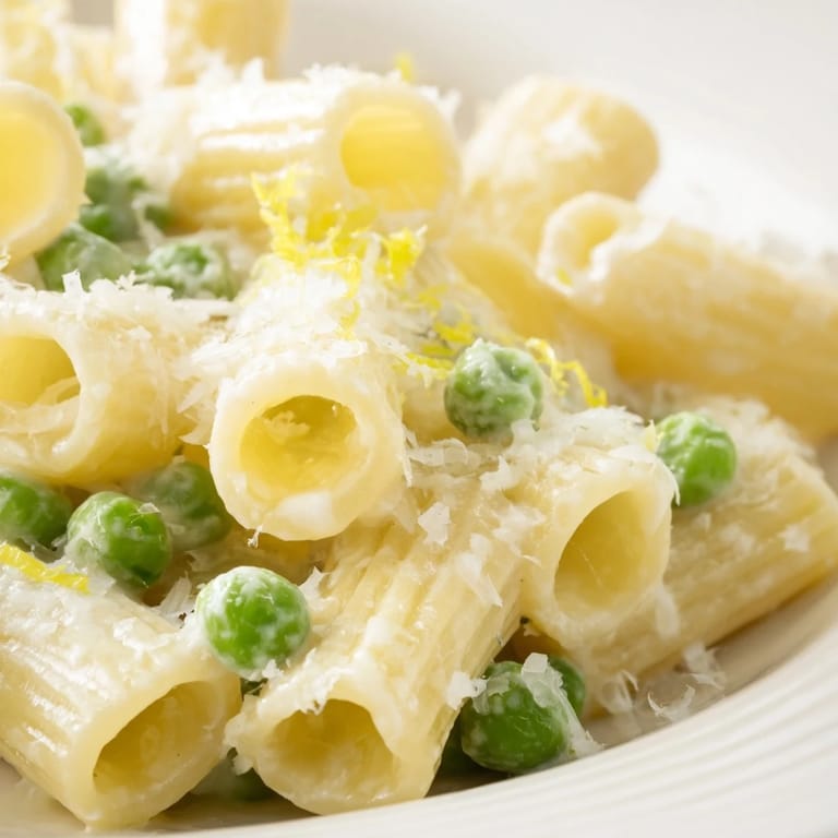 Vibrant green peas and zesty lemon ricotta sauce cling to hearty rigatoni noodles, ready to serve for a quick vegetarian dinner.