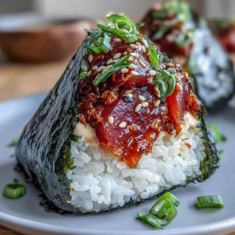 Japanese spicy tuna onigiri with seasoned rice, creamy tuna filling, and toasted sesame seeds for crunch.  