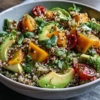 A vibrant tropical quinoa salad with ripe mango, creamy avocado, and zesty lime dressing for a refreshing summer meal.  