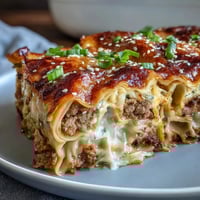 Delicious dumpling lasagna bake with ground pork and cabbage, golden layers of tender wrappers and savory filling baked to perfection.
