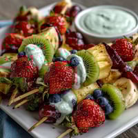 Fun Kid Lunch Bento Box with Fruit Skewers and Dip, featuring colorful strawberry and kiwi skewers, creamy vanilla yogurt dip, and whole wheat sandwiches in a divided lunchbox.  